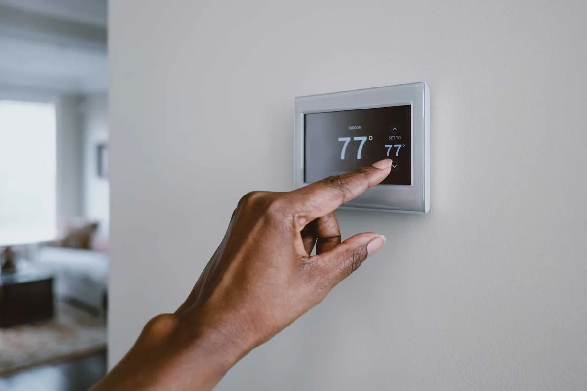 Homeowner adjusting a smart thermostat during HVAC maintenance